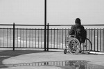 Persona con disabilità guarda il mare da una terrazza (foto in bianco e nero)