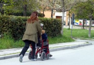 Donna spinge la carrozzina di un familiare con disabilità