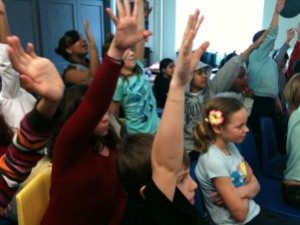 Bambini a scuola con le mani alzate