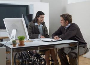 Donna con disabilità al tavolo di lavoro, insieme a una persona non disabile
