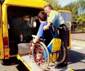 Ragazzo in carrozzina sale in un pulmino per il trasporto a scuola dei disabili