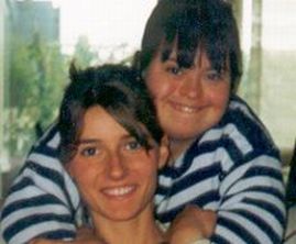 Giovane donna abbracciata da dietro dalla sorella con sindrome di Down