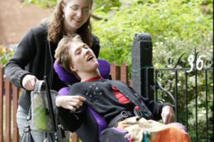 Giovane con disabilità in carrozzina, spinto da una donna
