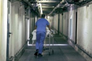 Infermiere che spinge una barella in un corridoio di ospedale, fotografato di spalle