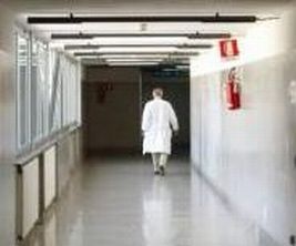 Medico fotografato di spalle, mentre si allontana in un corridoio di ospedale