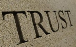 Scritta "TRUST" scolpita in un muro