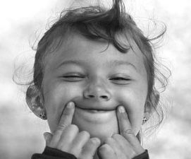 Foto in bianco e nero di una bimba che sorride e fa una smorfia