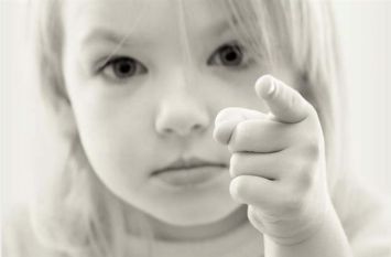 Foto in bianco e nero di bimba con un dito puntato