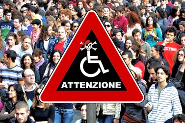 Creazione grafica con un cartello di pericolo al centro, riempito dal logo della disabilità, "travestito da pirata", in mezzo a una moltitudine di persone