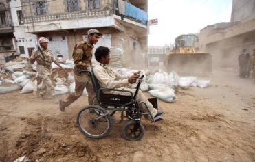 Persona con disabilità nello Yemen, spinta da un giovane soldato