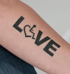 Braccio con il tatuaggio "Love" e al posto della O una carrozzina su un cuore
