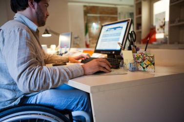 Persona con disabilità in carrozzina al lavoro al computer
