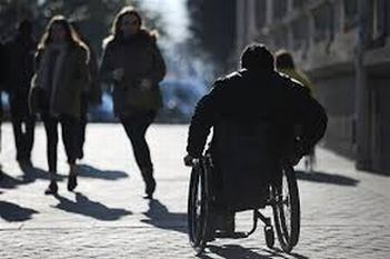 Foto in bianco e nero di uomo in carrozzina che incrocia altre persone non disabili