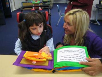 Bambina con disabilità visiva utilizza un libro tattile