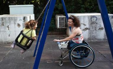 Madre con disabilità motoria fa giocare la propria bimba sull'altalena