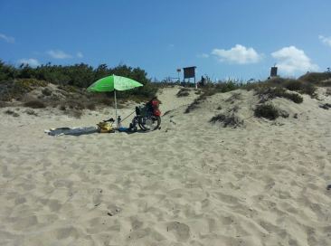 Persona in carrozzina in mezzo alla sabbia di una spiaggia