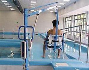 Persona con disabilità motoria entra in piscina tramite un sollevatore
