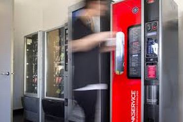 Persona davanti a distributori automatici di caffè e altri prodotti
