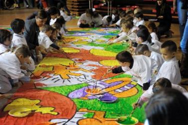 Bambini di scuola che disegnano su un grande lenzuolo