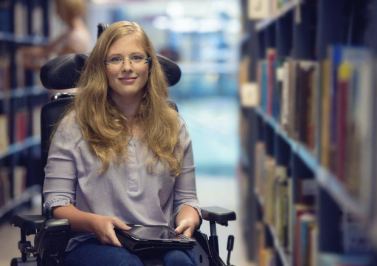 Giovane donna con disabilità motoria in biblioteca