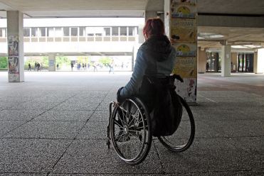 Donna con disabilità in carrozzina, fotografata di spalle