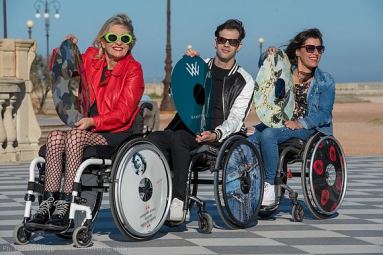 Tre persone con disabilità indossano e mostrano i copriruota realizzati da Vanity Wheel