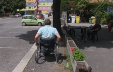 Persona con disabilità a Pomezia (Roma), ferma davanti a un paolo sul marciapiede