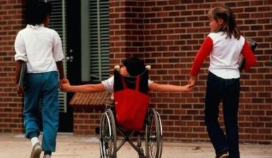 Una ragazza in carrozzina tra due ragazze senza disabilità