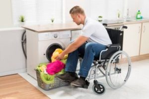 Persona con disabilità in carrozzina che carica una lavatrice