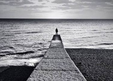 Persona sola davanti al mare, in fondo a una passerella