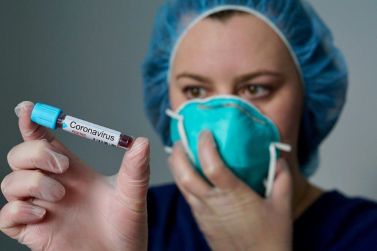 Un'infermiera con la mascherina e una fialetta di paziente positivo al coronavirus