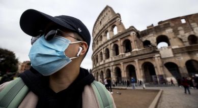 Persona con mascherina davanti al Colosseo
