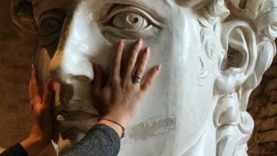 Mani che toccano il volto di una scultura