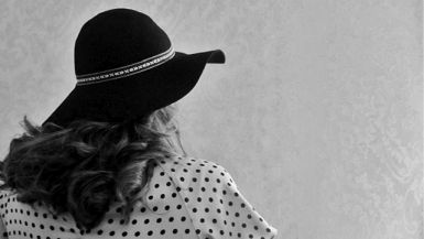 Foto in bianco e nero di donna con cappello di spalle