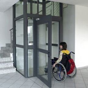 Persona con disabilità in carrozzina davanti a un ascensore condominiale