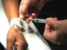 Medico applica una siringa sul braccio di un paziente: immagine simbolica dell'accanimento terapeutico