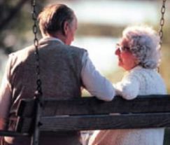 Un uomo e una donna anziani seduti su una panchina e fotografati di spalle