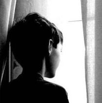 Foto in bianco e nero di bimbo che guarda fuori dalla finestra