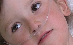Primo piano di viso di bimbo malato, con cannule nel naso
