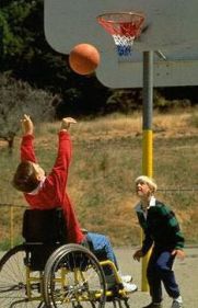 Ragazzino in carrozzina gioca a basket con un altro non disabile