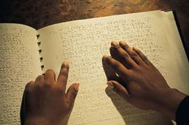 Lettura con le mani di libro in Braille