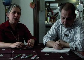 Scena tratta dal documentario: due genitori seduti a un tavolo, uno disegna