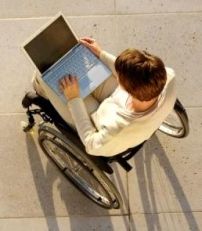 Persona in carrozzina con un computer sulle gambe, fotografata dall'alto