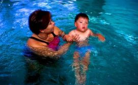 Bimbo con disabilità in piscina insieme a una donna adulta