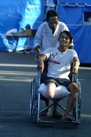 Ragazzo con gamba amputata e in carrozzina presso una tendopoli, insieme a un adulto