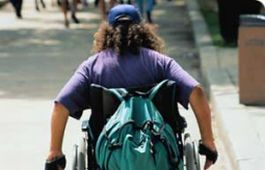 Giovane paraplegico in carrozzina fotografato di spalle
