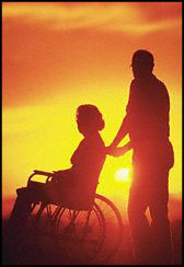 Persona con disabilità e accompagnatore. Sullo sfondo un tramonto