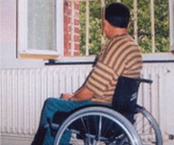 Persona con disabilità in casa davanti a una finestra con le sbarre