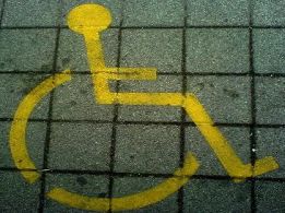 Simbolo dell'handicap dipinto in giallo sull'asfalto, con una grata sopra