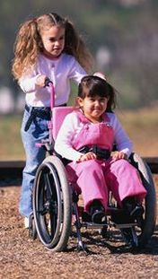 Bimba in carrozzina spinta da altra bambina non disabile
